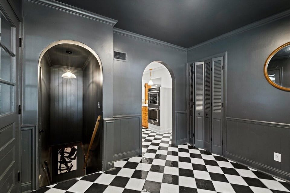 Main-level garage entryway with classic black-and-white tile leading to the kitchen and basement. An open, connected layout built for easy movement throughout the home.