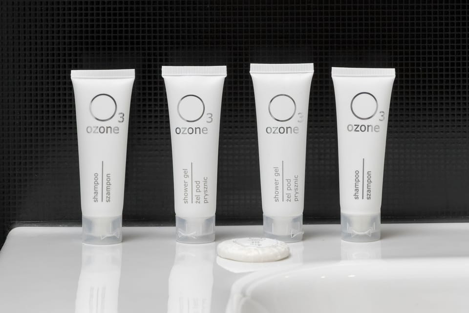 Four identical white tubes of toiletries are lined up neatly on a white porcelain ledge in the bathroom. This detail emphasizes the attention to guest comfort and cleanliness.