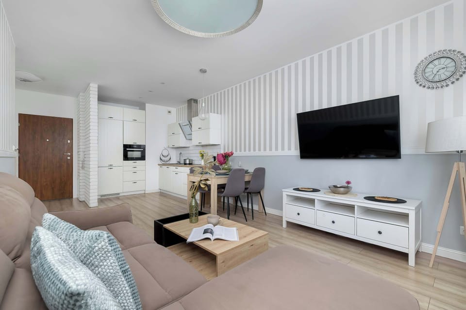 Another view of the cozy living space, featuring a different angle of the brown sofa and coffee table.  The wide window allows natural light to brighten the room.