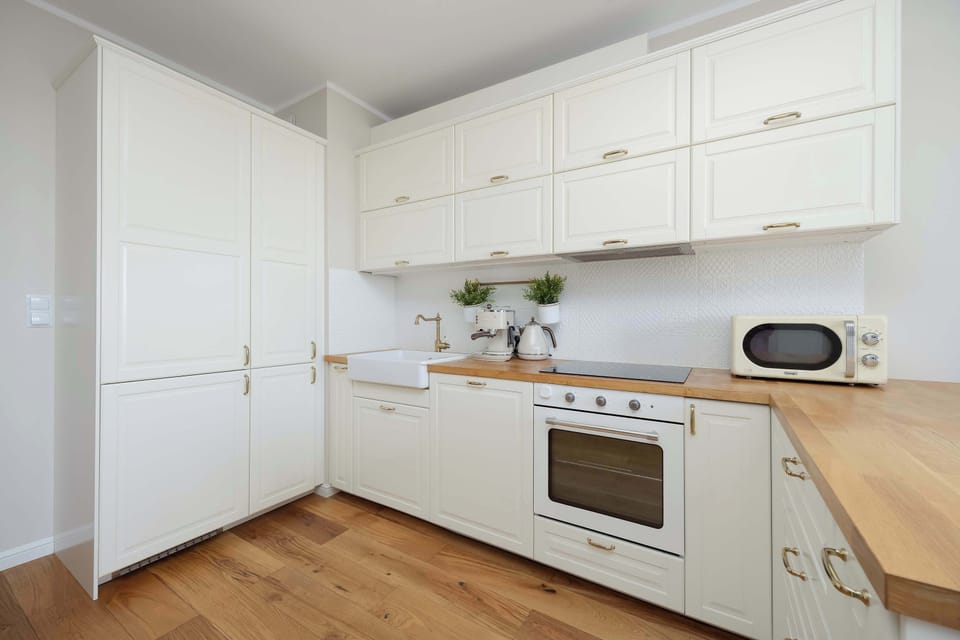 A kitchen corner with an oven, stovetop, and white cabinets extending to the ceiling.