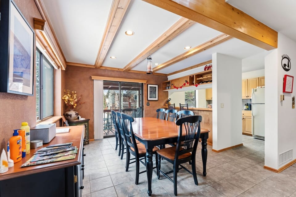 Gather around this rustic dining table under gorgeous exposed beam ceilings. Natural light flows through windows, creating the perfect space for your memorable meals together.