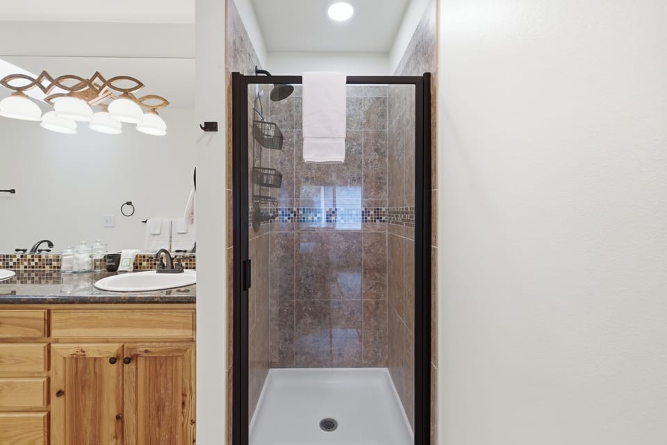 Step into your spacious tiled shower with elegant mosaic accents and convenient built-in storage for all your essentials.