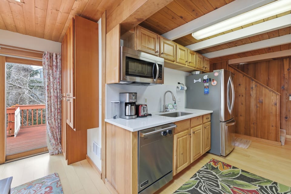 Your cozy mountain kitchen features warm wood beams, modern appliances, and opens to a private deck surrounded by peaceful winter trees.