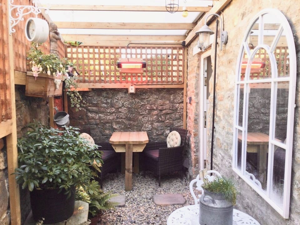 Partly covered rear courtyard with dining area and heater.