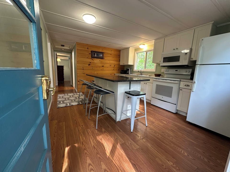 Your fully equipped kitchen features white appliances, an island for casual meals, and warm wood accents creating a cozy cooking space.