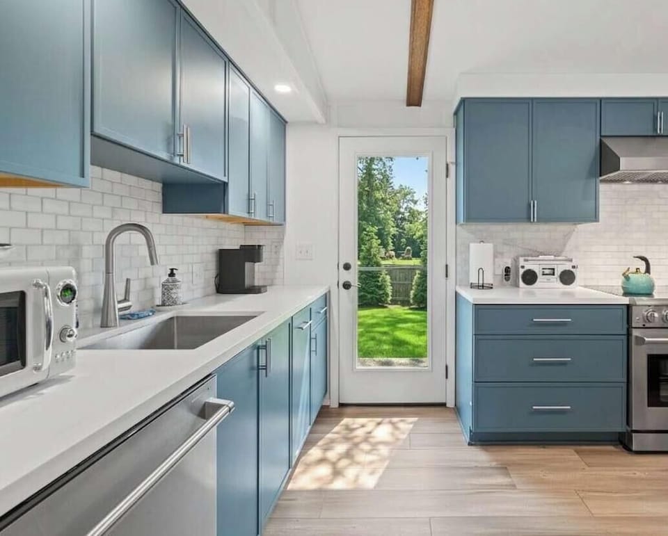 Fully equipped with sleek blue cabinetry, quartz counters, and stainless steel appliances, this clean, open kitchen has everything you need—whether you're preparing quick family snacks or a full holiday feast. Best of all, you can walk straight out t
