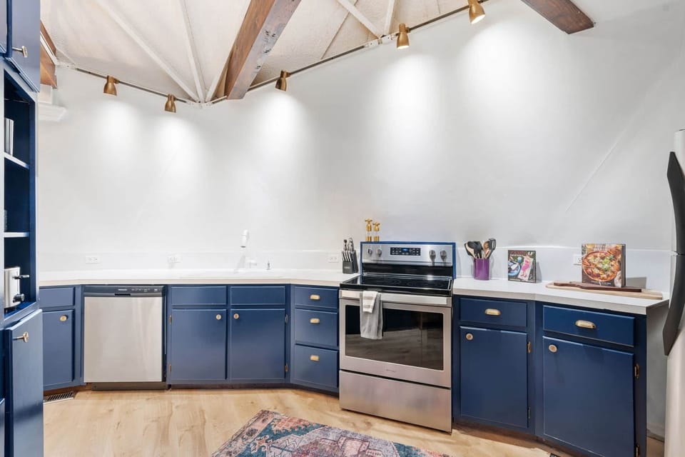 Fully equipped kitchen with stainless appliances and stylish blue cabinetry.