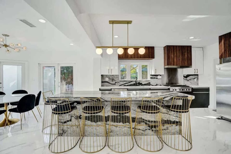 Elegant gold stools and a massive island create a social kitchen hub.