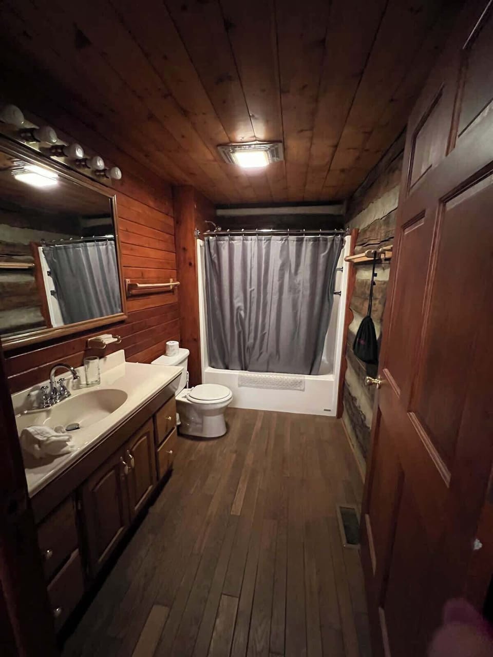 The attached bathroom for the downstairs bedroom. The vanity lighting and overhead light/fan illuminate the room well.