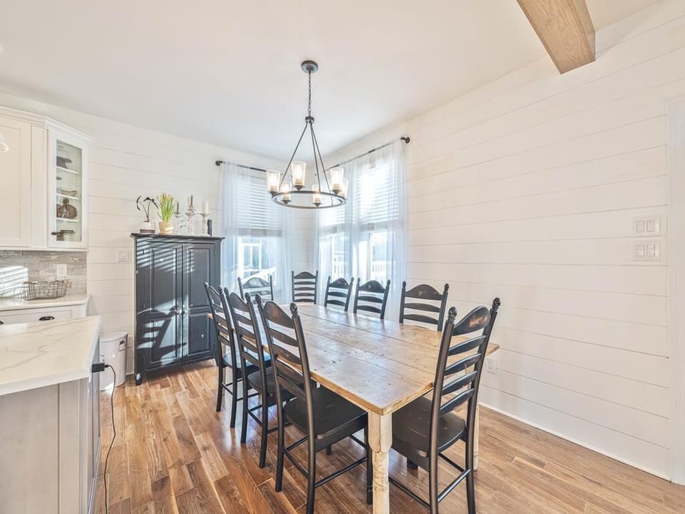 Share laughter and stories at this spacious dining table, bathed in natural light from large windows.