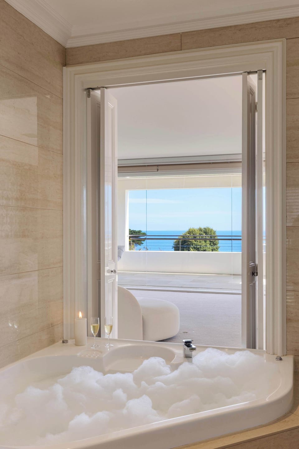 Indulgent soaking tub in master bedroom framed by tranquil views — your own private day spa.