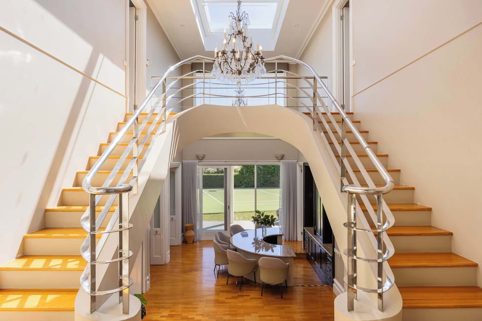 A dramatic double staircase and chandelier create a striking sense of arrival.