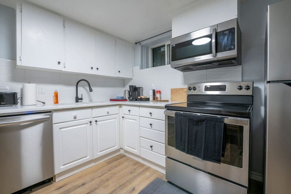 Modern white kitchen with stainless steel appliances.