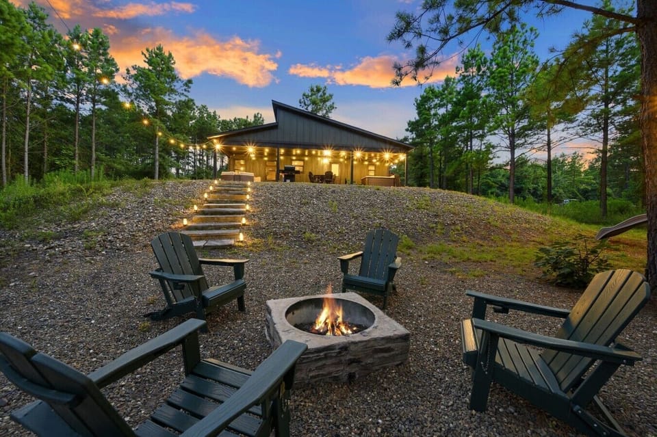 Fire pit seating under string lights with the cabin glowing in the background.