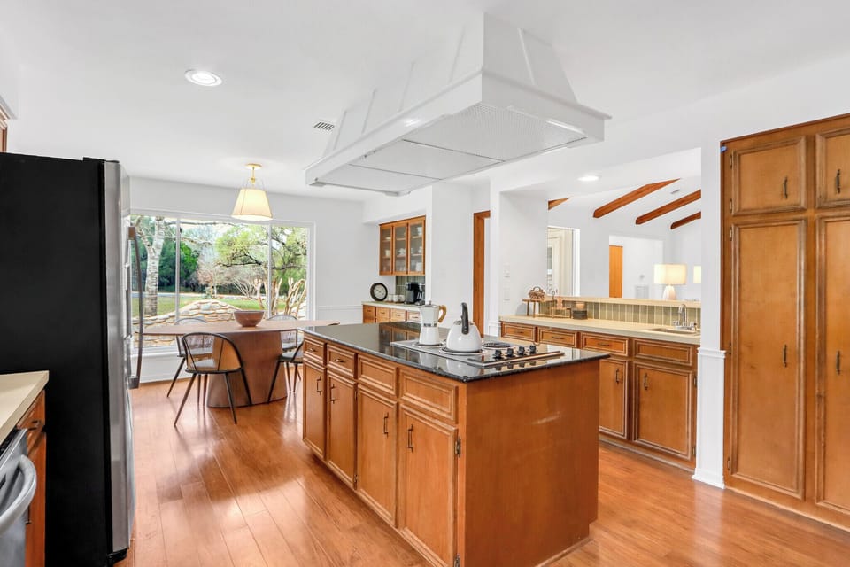 Your spacious kitchen invites culinary adventures with granite counters, professional appliances, and warm wood floors flowing into a bright dining area.