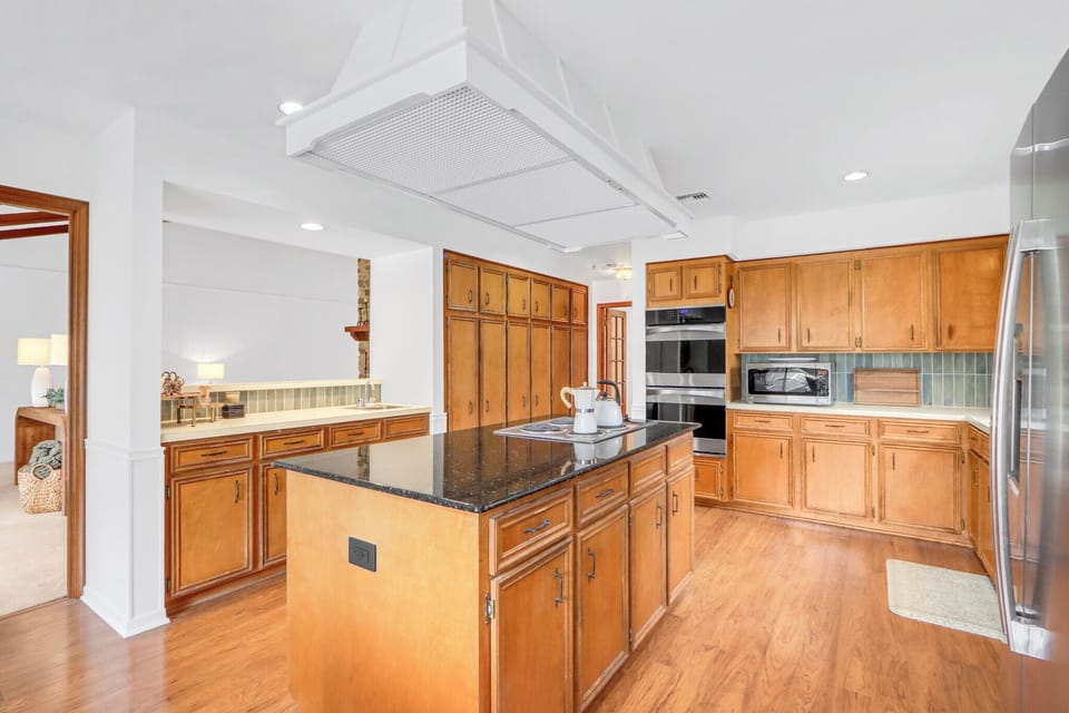 Spacious kitchen with granite island, wood cabinets, and modern appliances perfect for preparing your favorite meals together.