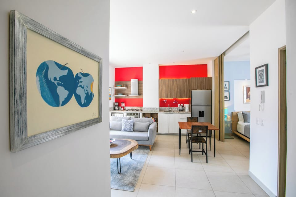 Settle into your modern open-plan space where bold red kitchen accents meet contemporary comfort, perfect for cooking and relaxing.