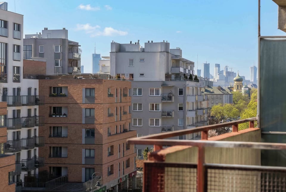 An elevated view from the apartment displays a mix of residential buildings and the city skyline in the distance.