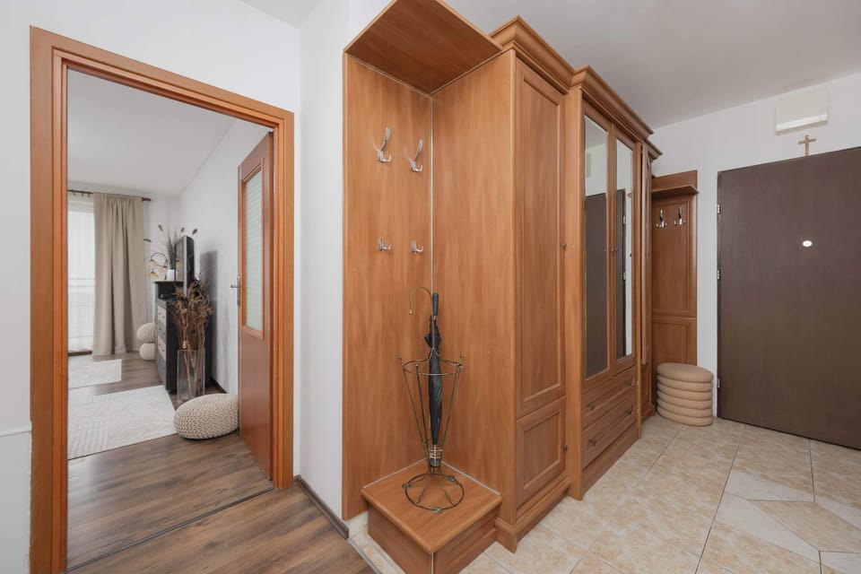 An entryway features a large wooden coat rack with a mirror and a shoe storage unit for guest convenience.