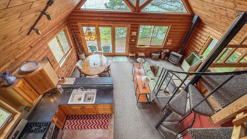 Your private loft cabin offers soaring windows that flood the open living space with natural light from surrounding trees.