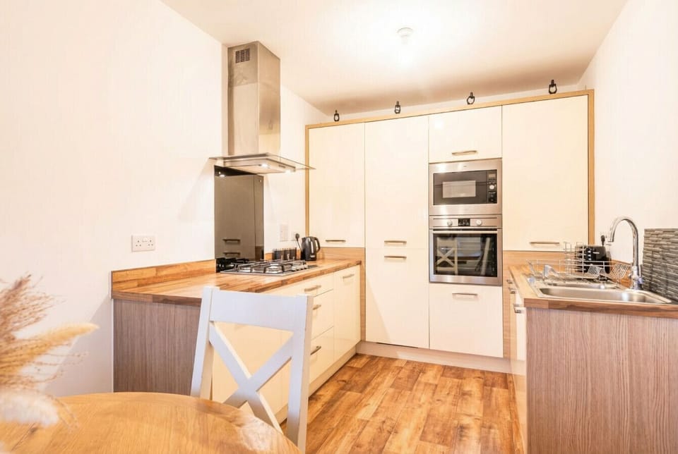 Warm-toned kitchen with AEG double oven, gas hob, extractor and everything you need to cook comfortably.