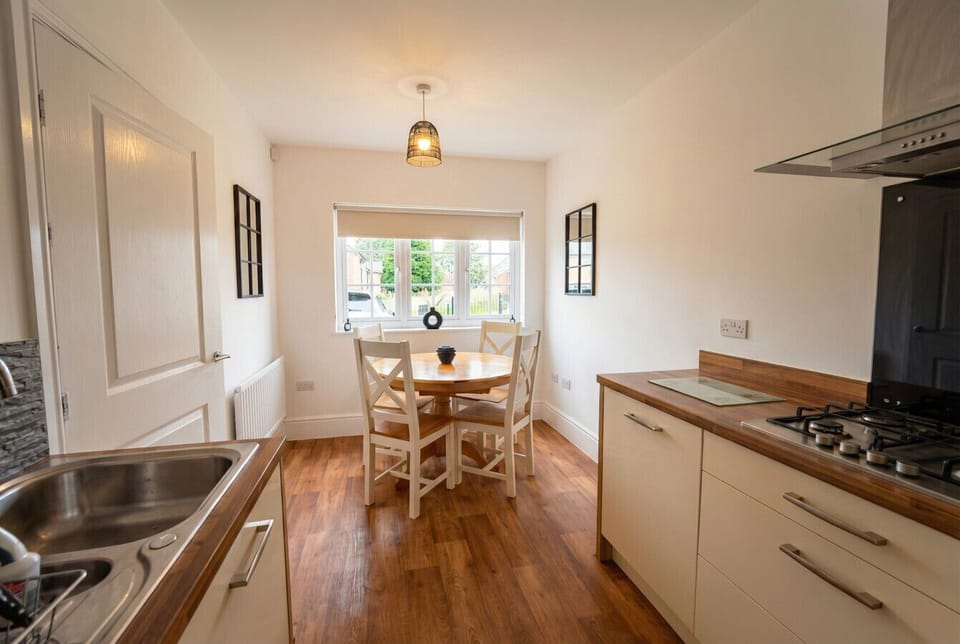 Bright kitchen-diner with a round wooden table for four and pretty garden views through the bay window.
