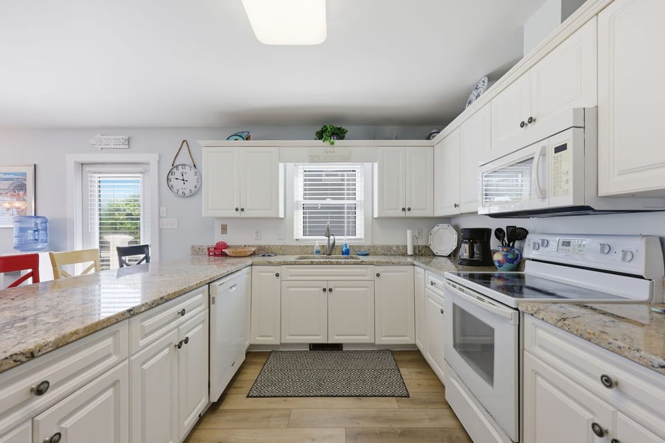 A bright, fully equipped kitchen awaits you with modern appliances, granite counters, and warm white cabinetry—perfect for preparing your favorite meals while on vacation.