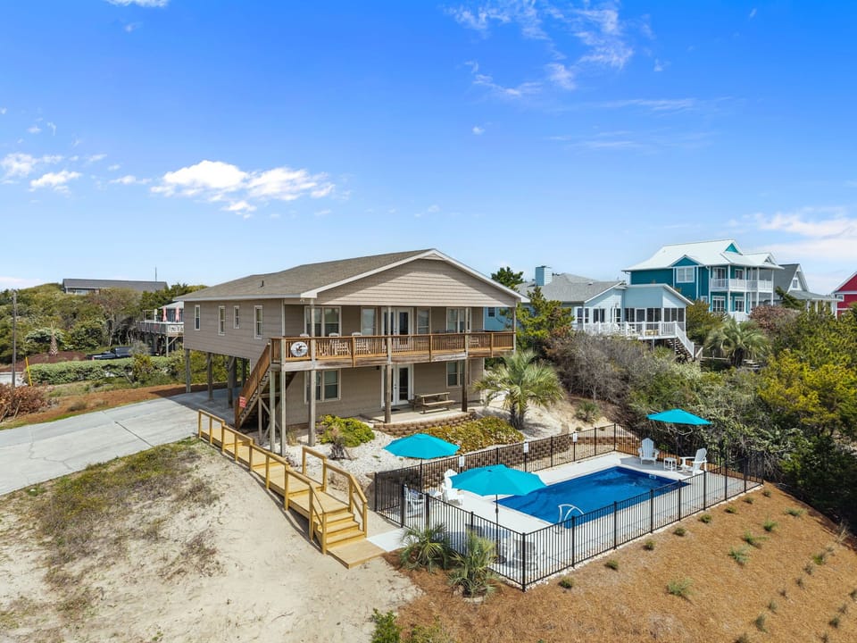 Elevated beach house with private pool surrounded by coastal homes in a charming neighborhood setting.