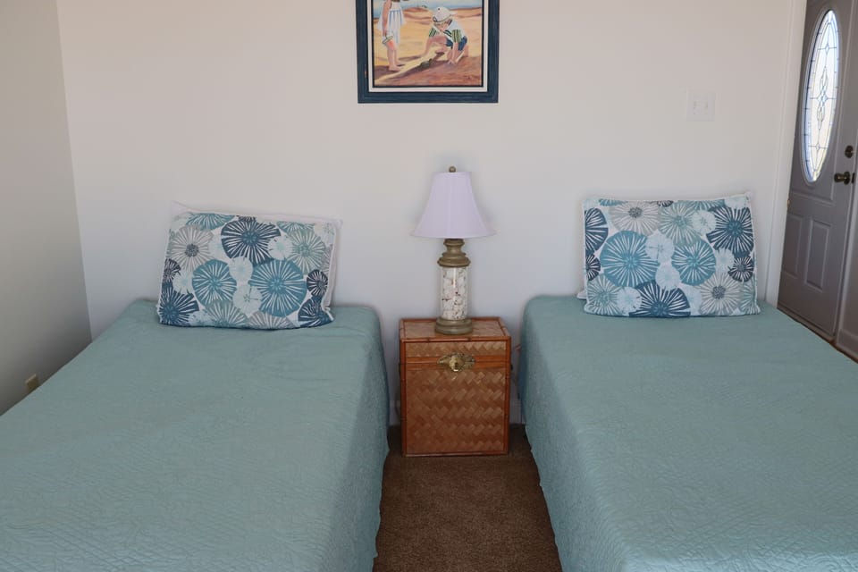 Rest peacefully in your twin bed setup with coastal-themed pillows and warm ambient lighting creating the perfect retreat.