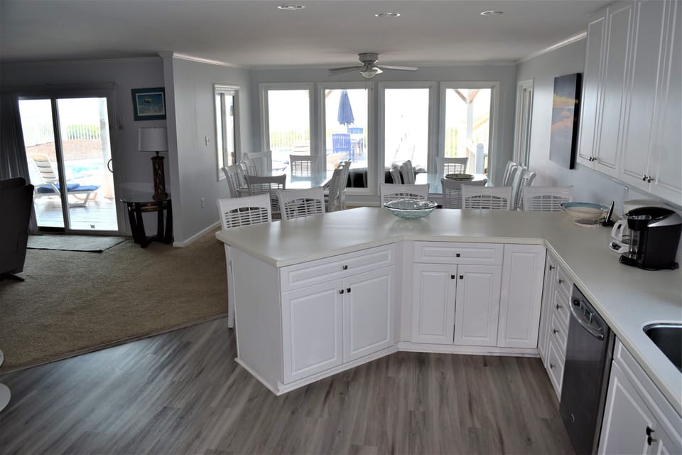 Your bright kitchen island opens to a dining area with pool views through expansive windows.