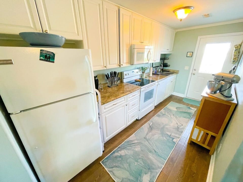 Your fully equipped kitchen awaits with granite counters, white appliances, and coastal charm for memorable meal prep during your stay.