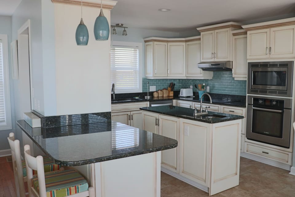 Your fully equipped kitchen features granite counters, stainless appliances, and coastal charm with turquoise accents for memorable meal prep.