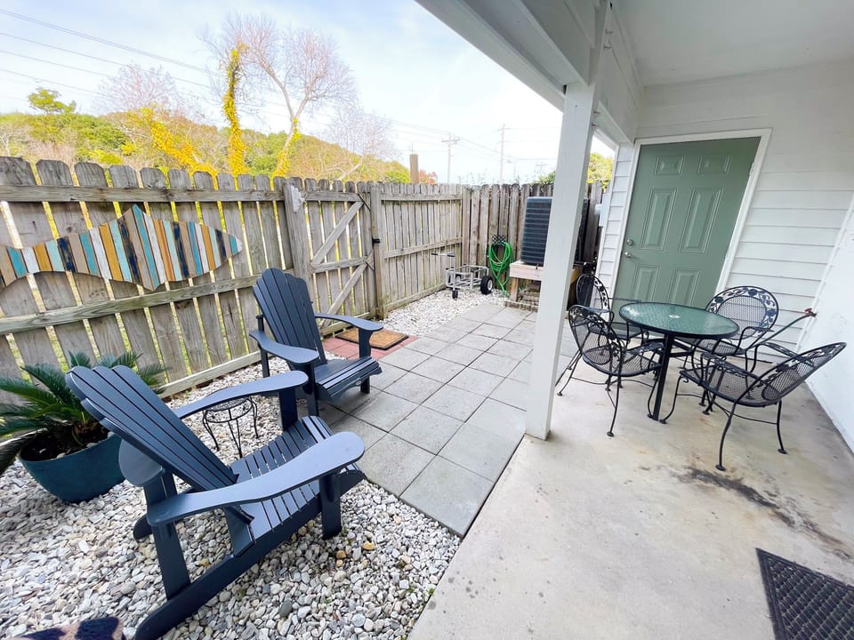 Your private covered patio features comfortable seating with both casual Adirondack chairs and elegant dining table—perfect for morning coffee or evening meals outdoors.