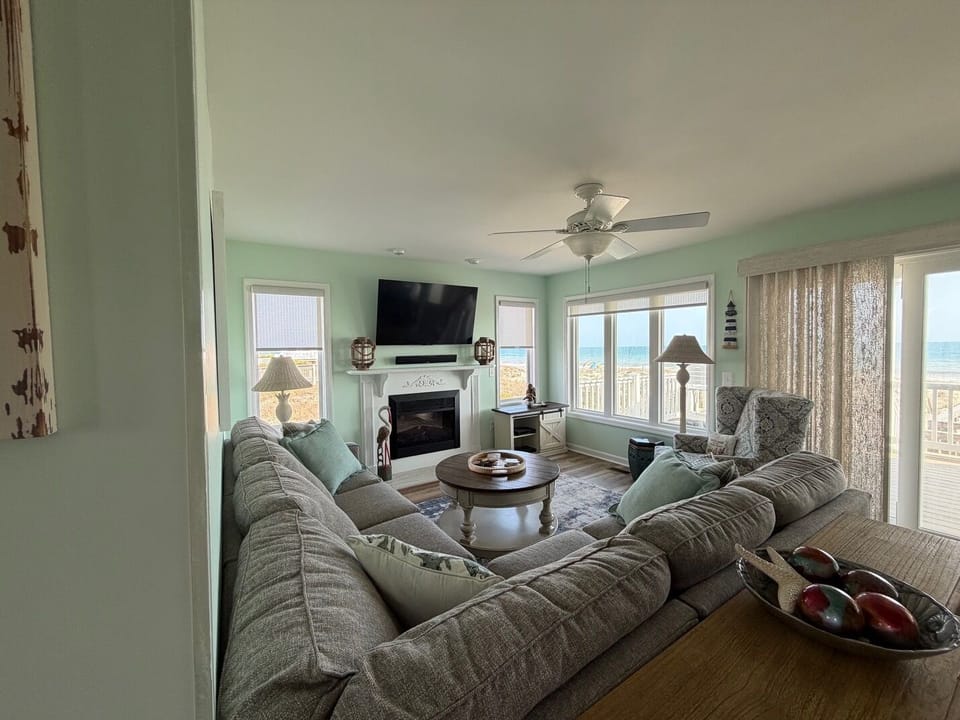 Sink into plush coastal comfort while ocean views fill your windows and warmth from the fireplace creates perfect evening ambiance.