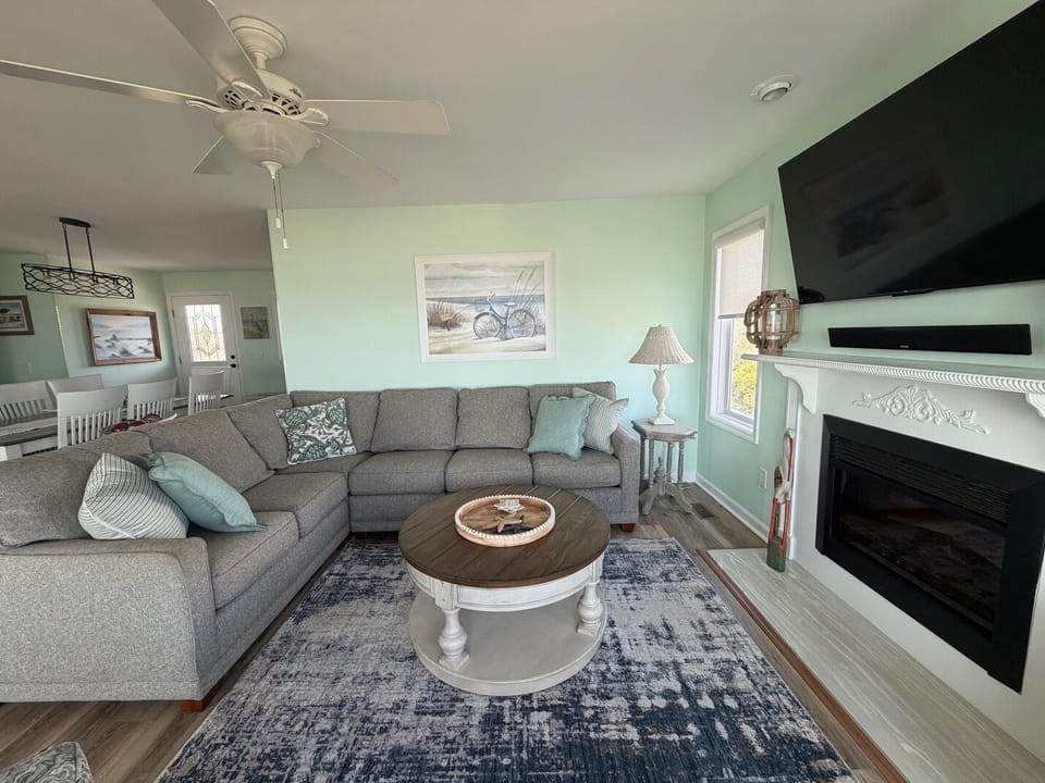 Settle into your cozy living room with plush sectional seating, where soft mint walls and a warm fireplace create the perfect retreat for relaxation.