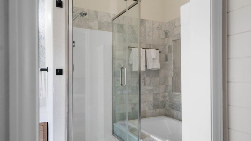 Beautifully finished shower area showcasing neutral tile accents, glass doors, and a bright, spa-like atmosphere.