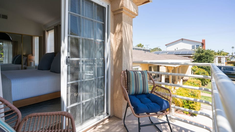 Bright outdoor balcony space connected to the bedroom, featuring comfortable seating and a peaceful neighborhood view. A relaxing spot to enjoy fresh air and morning coffee.