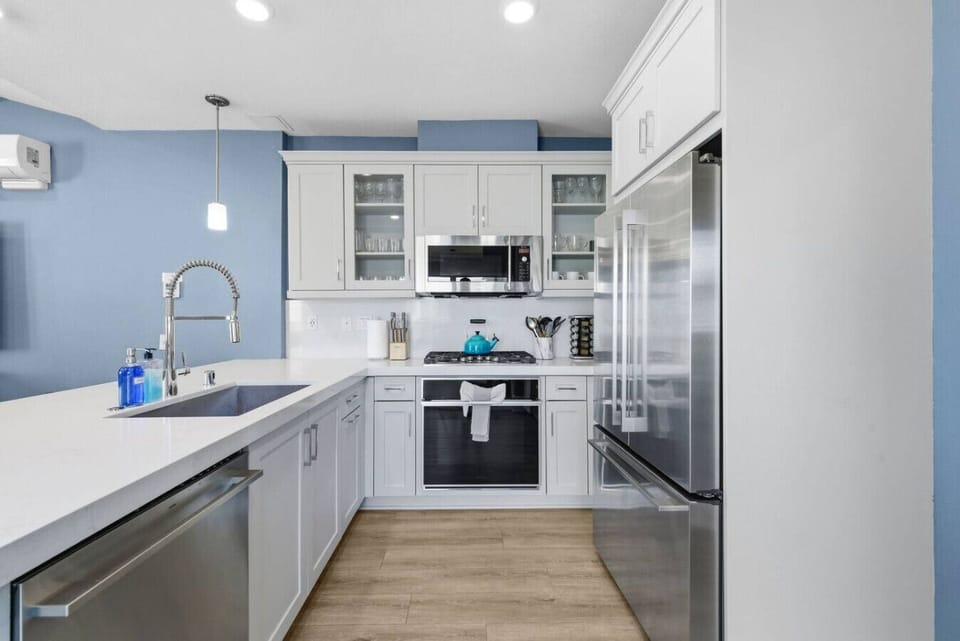 Chef`s kitchen with stainless steel French door refrigerator, gas range, microwave, dishwasher, and ample white cabinet storage for the whole group