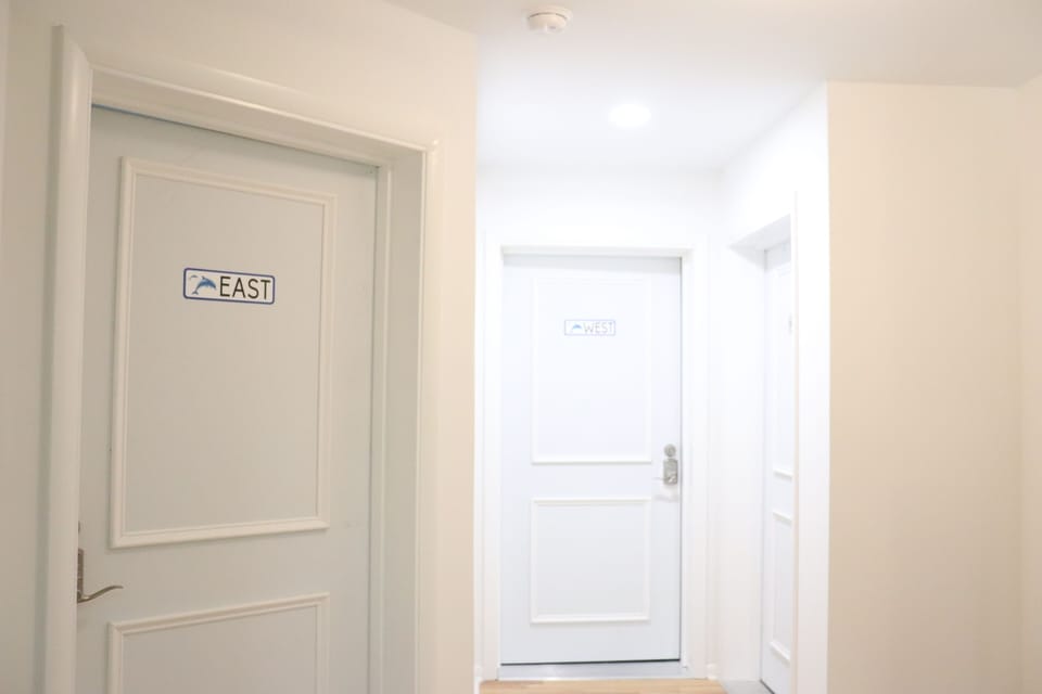 Your personal suite awaits behind this charming door, marked East—simple, coastal touches guide you to your quiet retreat.