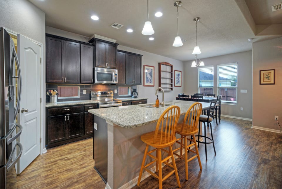 Modern kitchen featuring a large granite island and designer pendant lights.