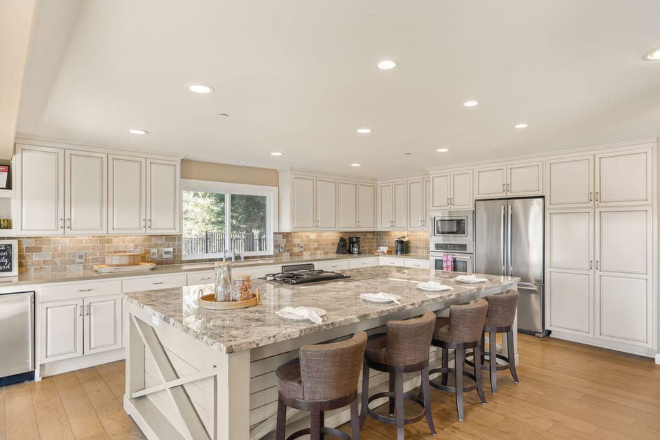 Expansive white kitchen with a massive granite island and breakfast bar seating, (Main House)