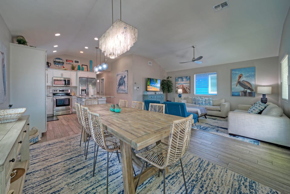 Large dining table with seating for the whole group, set within a bright coastal-style living room.