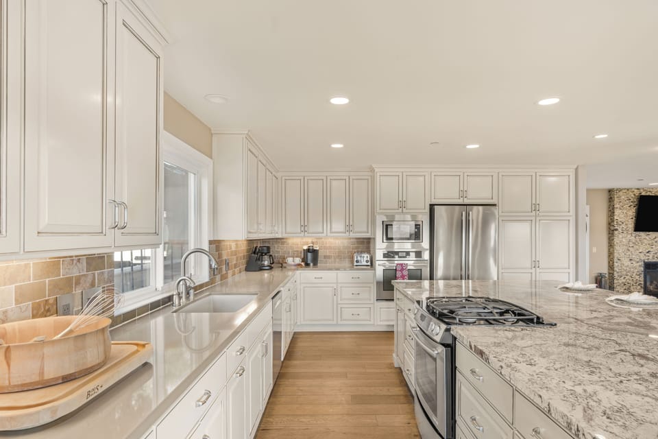 Bright kitchen view showcasing stainless steel appliances and white cabinetry. (Main house)