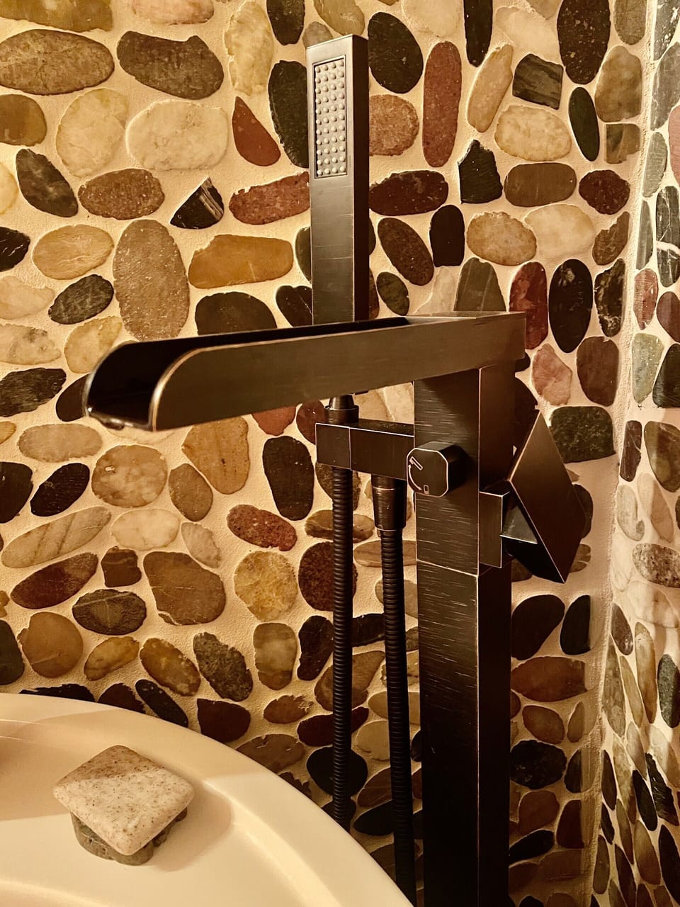 Rustic standing faucet, river rock walls and soaking tub.