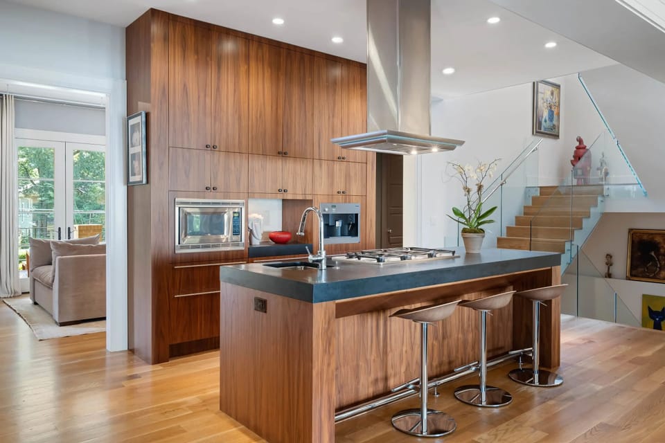 Sleek kitchen w/ stainless vent hood & warm wood cabinetry throughout