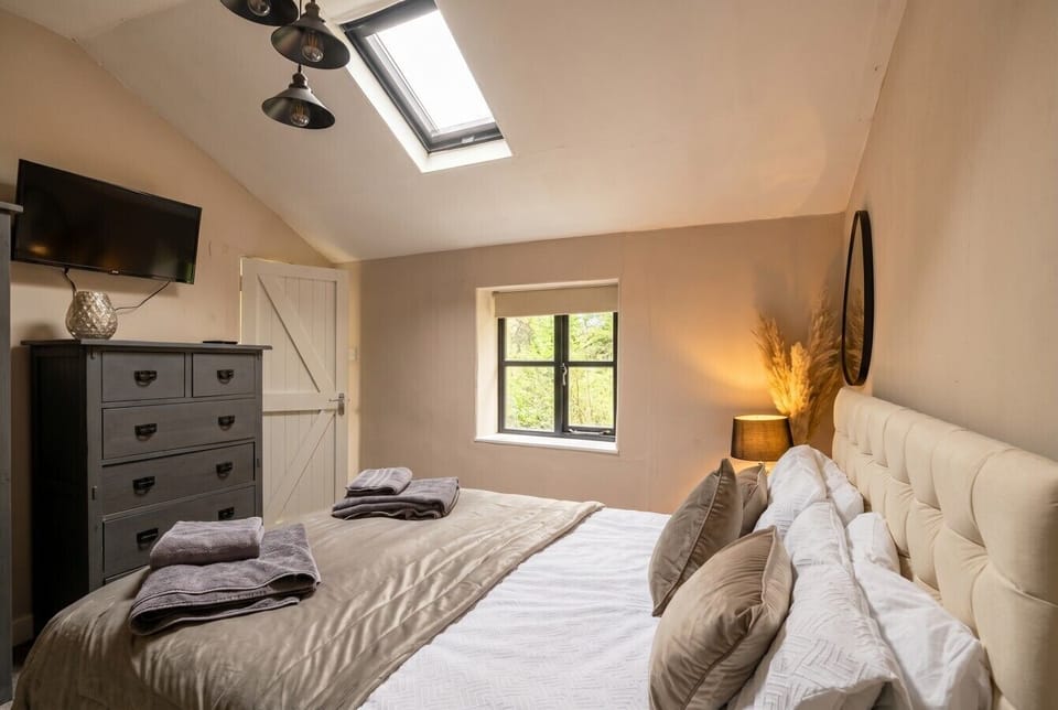 A restful double bedroom with a skylight, TV and chest of drawers for longer stays.