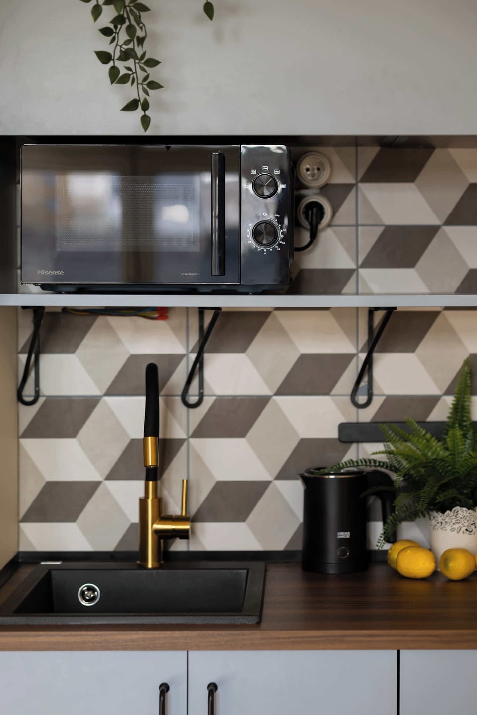 A kitchenette backsplash detail with patterned tiles and a countertop. Small items like jars and utensils are arranged neatly.