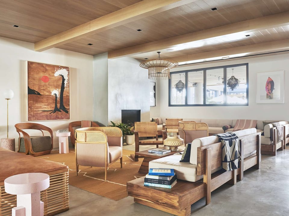 Large seating area with wood beams, woven chairs, and layered art