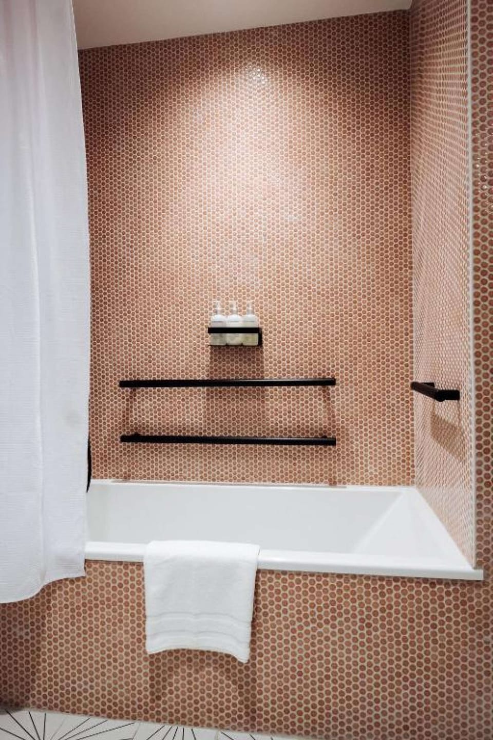 Bathtub with pink tile walls and black fixtures