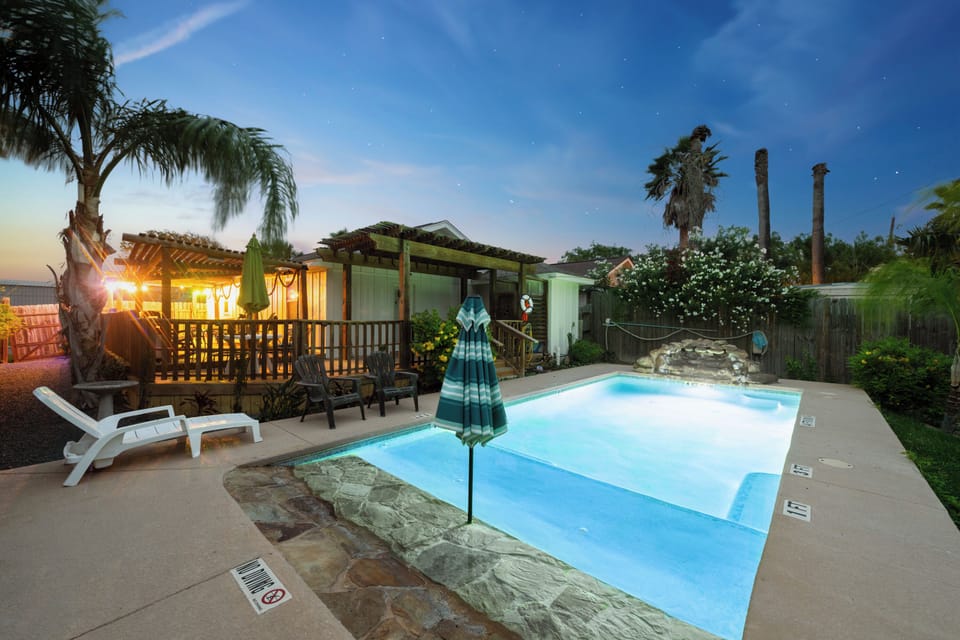 A tranquil private pool nestled within tropical landscaping offers the perfect oasis as twilight settles. Lounge poolside, surrounded by palm trees and lush greenery, with ambient lighting creating a serene evening atmosphere.